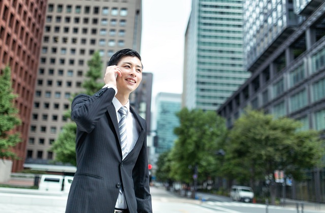 ビジネス街で携帯電話中の若手スーツ男性