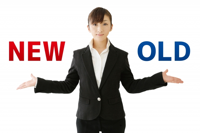 「NEW」「OLD」の文字を両手に持ったスーツ女性