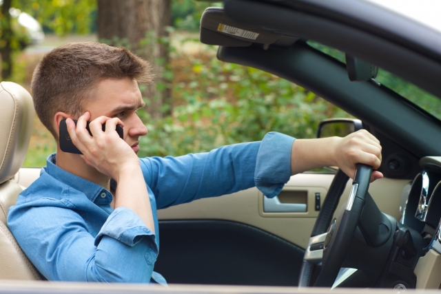 オープンカーを運転しながら電話している男性