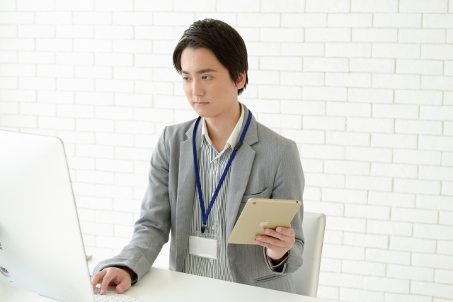 パソコンとタブレットで仕事する男性