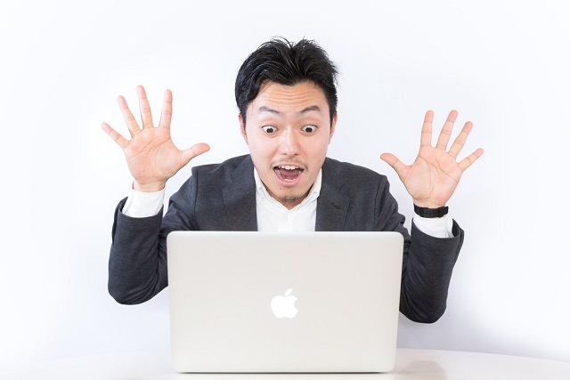 Macbookの前でびっくりする男性