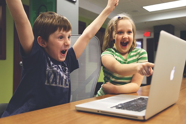 Macbookの前で喜んでいる子供2人